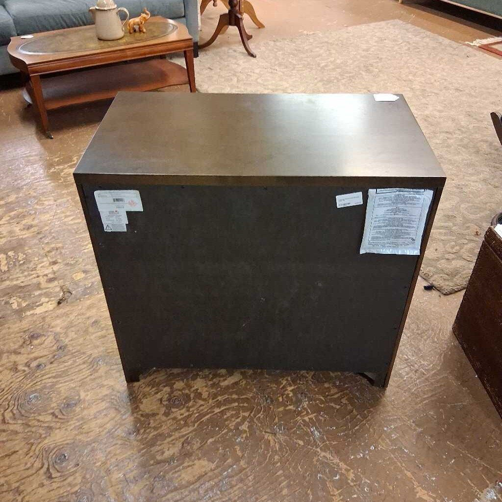 Black subwoofer on a wooden floor with furniture in the background