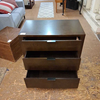 Brown dresser with multiple drawers on a wooden floor.