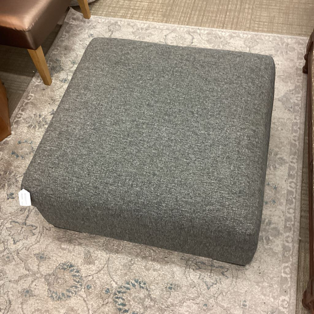Gray ottoman on a patterned rug