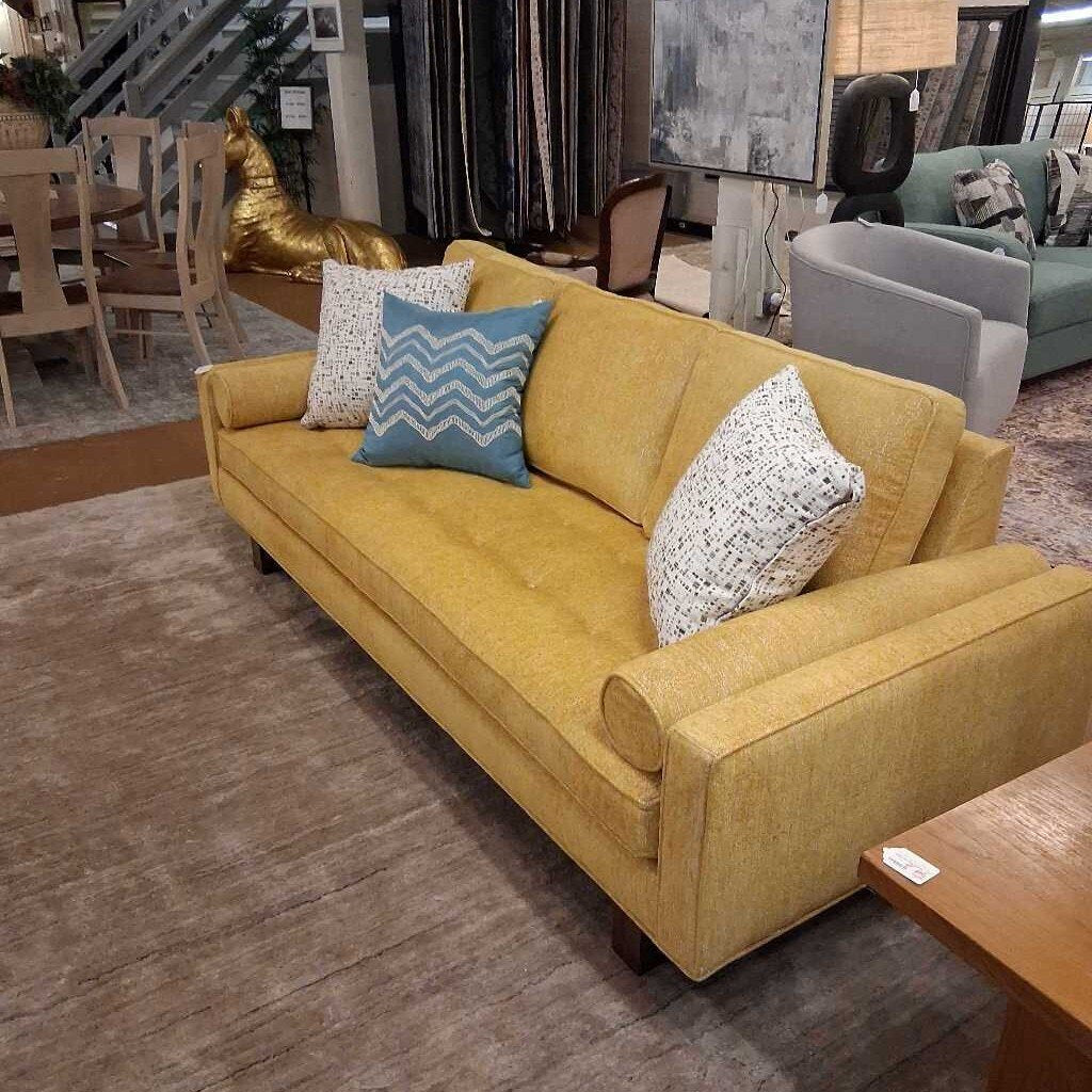 Yellow sofa with patterned cushions in a showroom setting