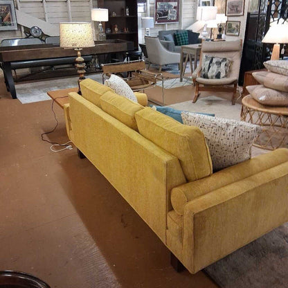 Yellow sofa in a room with various furniture and decor items.