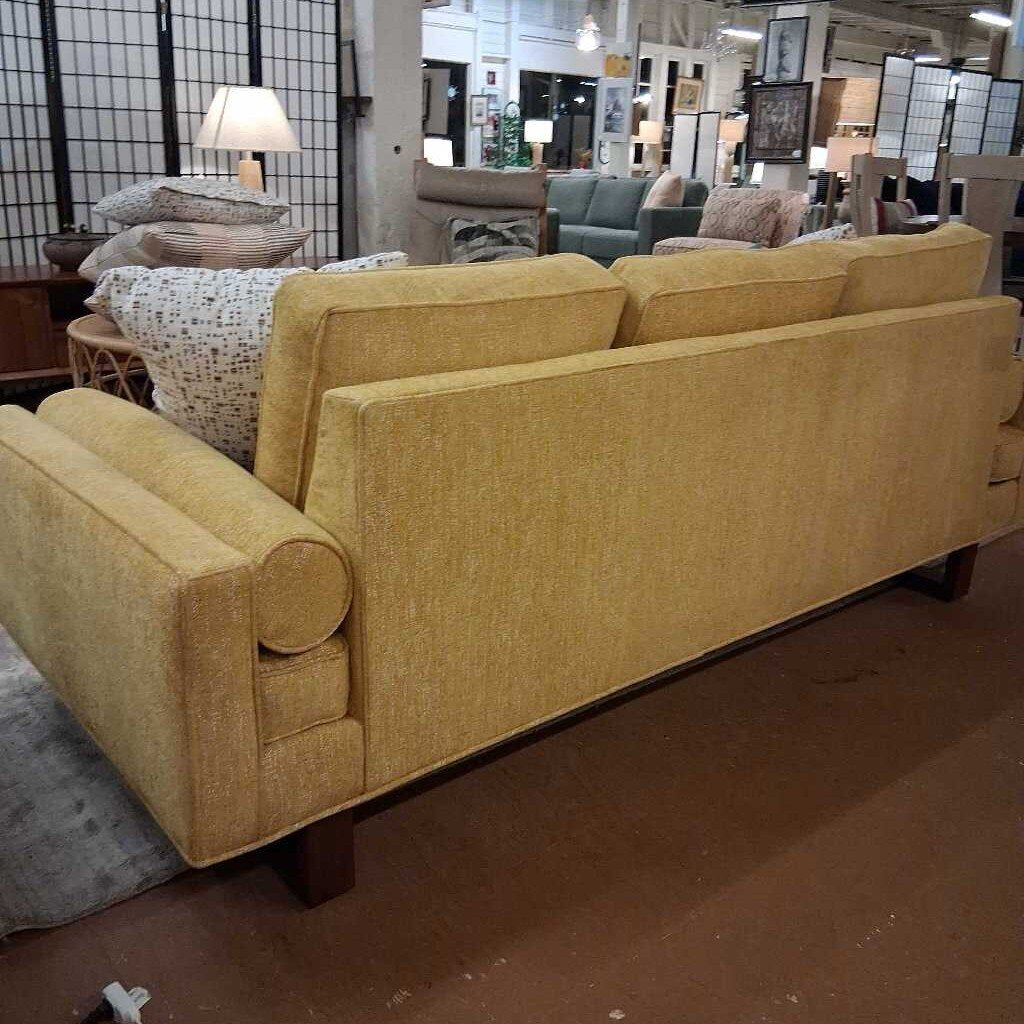 Yellow sofa in a showroom with other furniture in the background