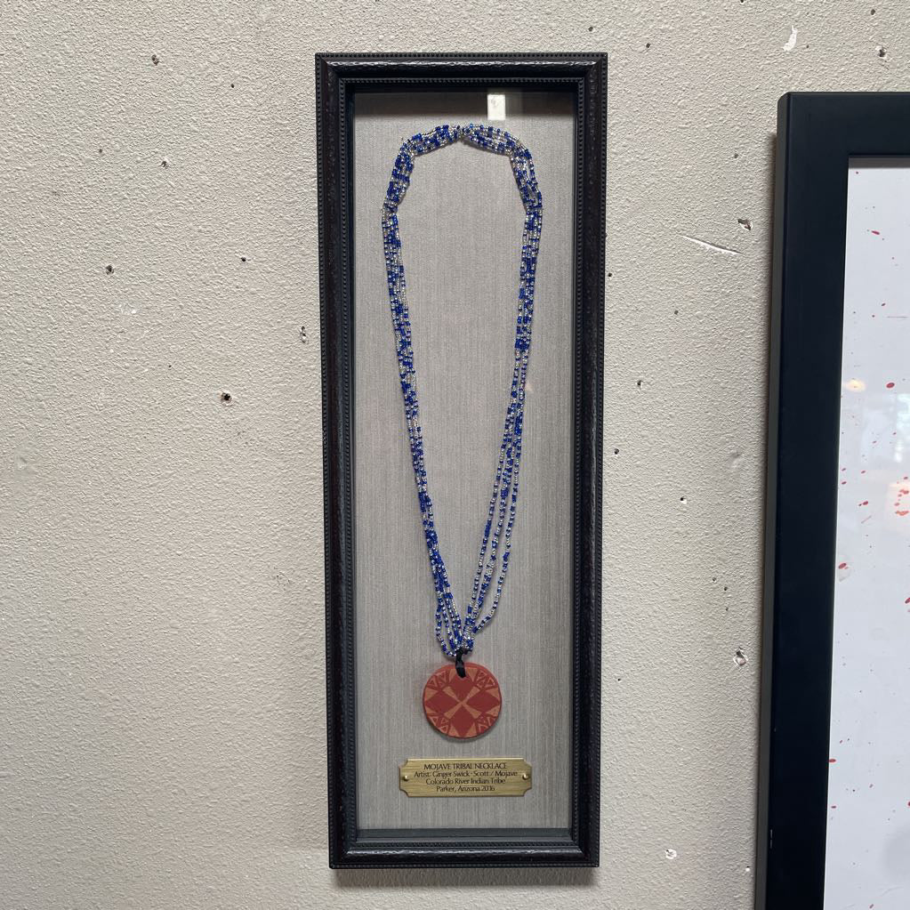 Necklace with a red pendant in a black frame on a textured wall