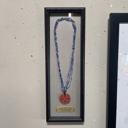 Necklace with a red pendant in a black frame on a textured wall