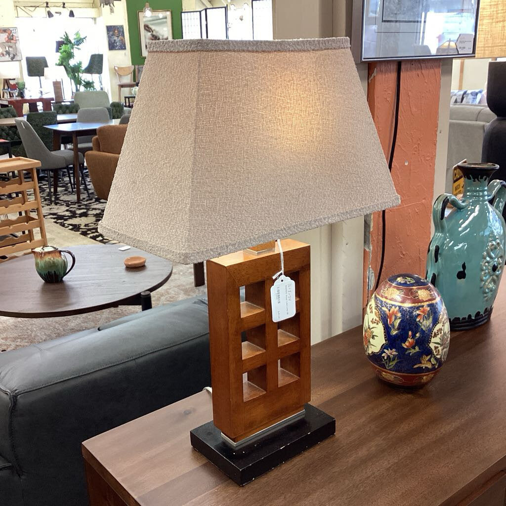 Lamp with a beige shade on a wooden base in a living room setting