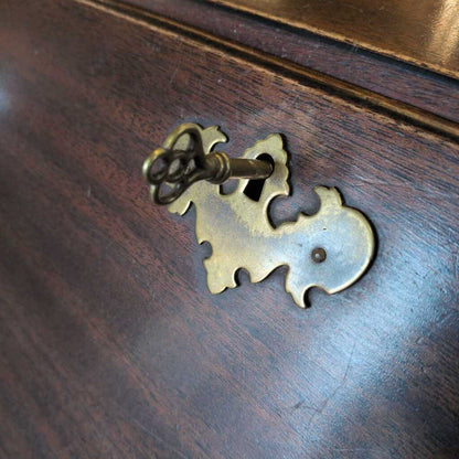 Brass keyhole with decorative cover on a wooden surface