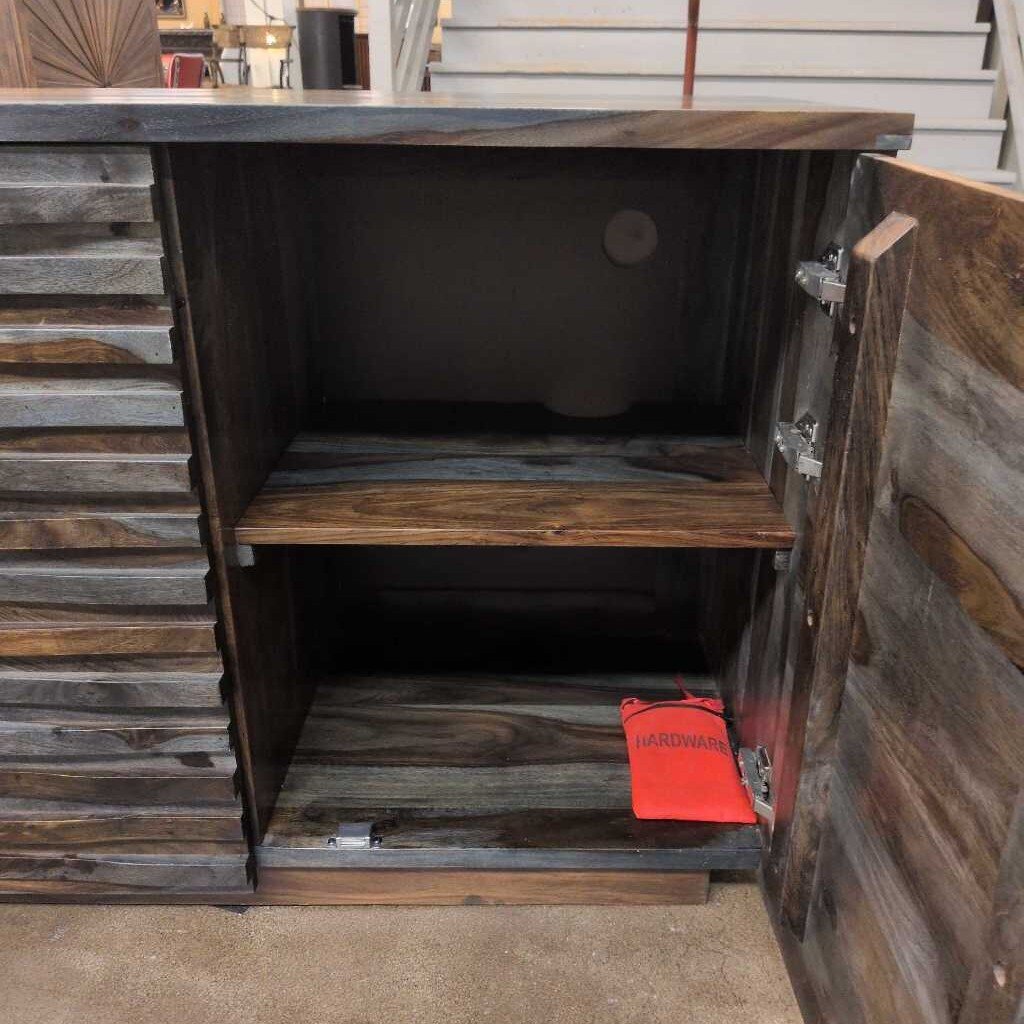 Wooden cabinet with open door revealing a red bag inside, against a rustic wooden wall.