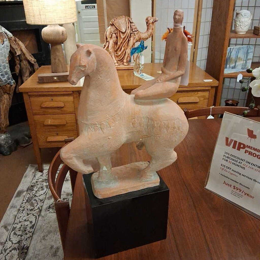 Statue of a horse on a wooden floor with a chair and lamp in the background