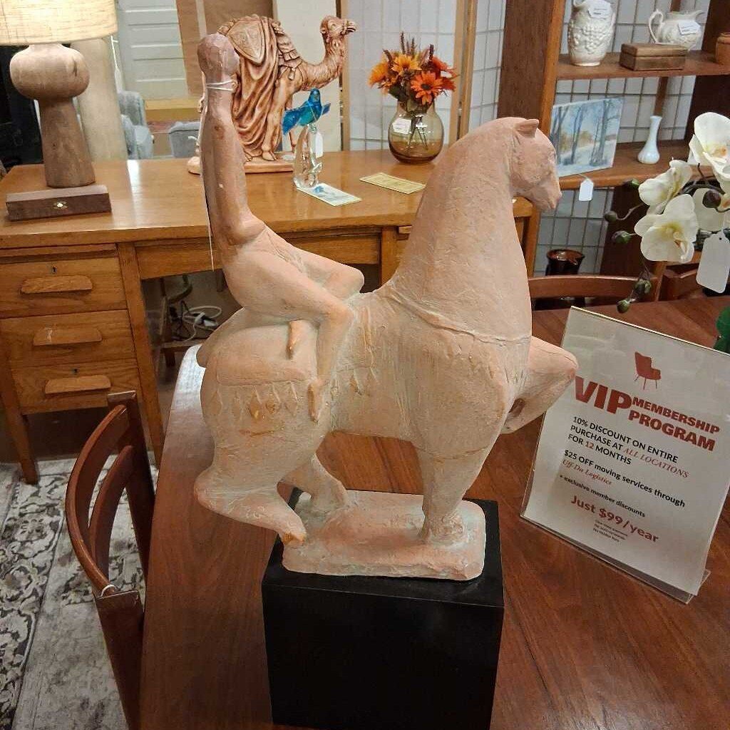 Decorative horse sculpture on a wooden table with a VIP membership program sign in the background.