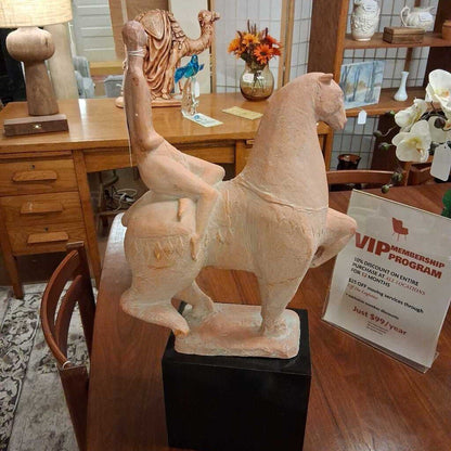 Decorative horse sculpture on a wooden table with a VIP membership program sign in the background.