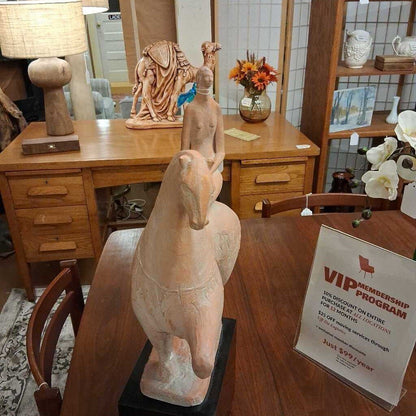 Decorative statues on a wooden table with a VIP membership program sign in a store setting.