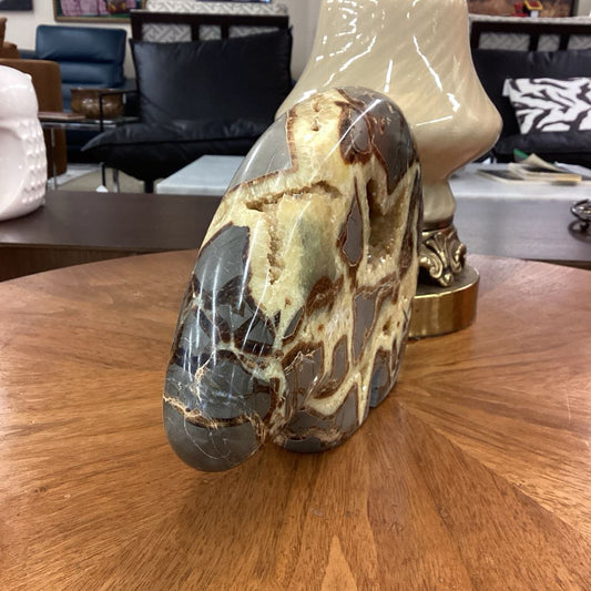 Marble-like stone sculpture of a horse head on a wooden surface with blurred background