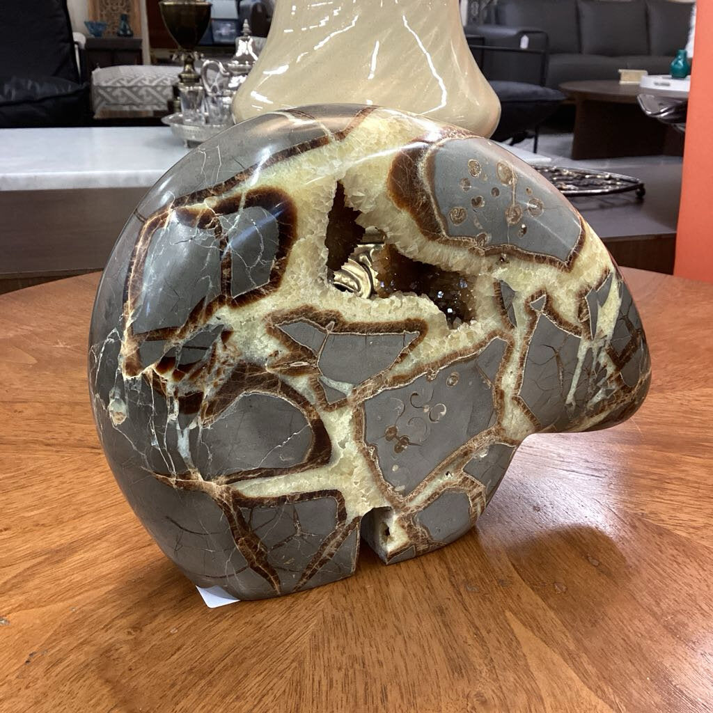Decorative stone sculpture on a wooden surface with a blurred indoor background