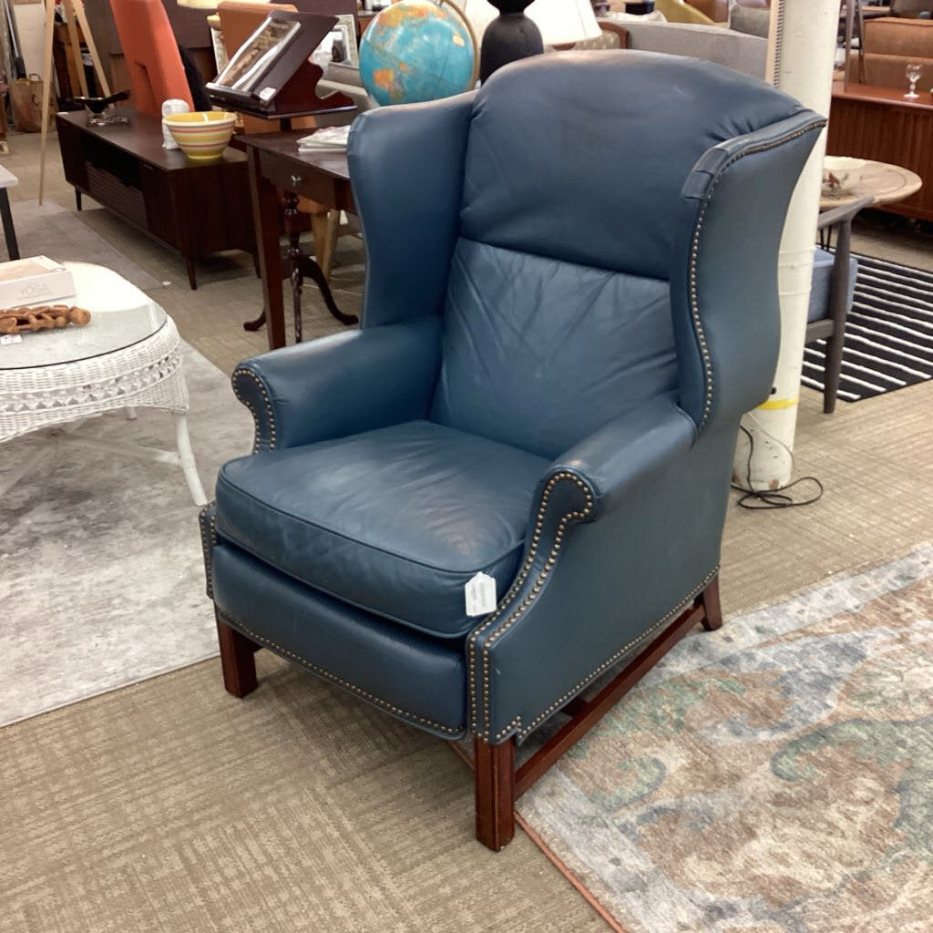 Blue leather armchair in a room with furniture and decor items.