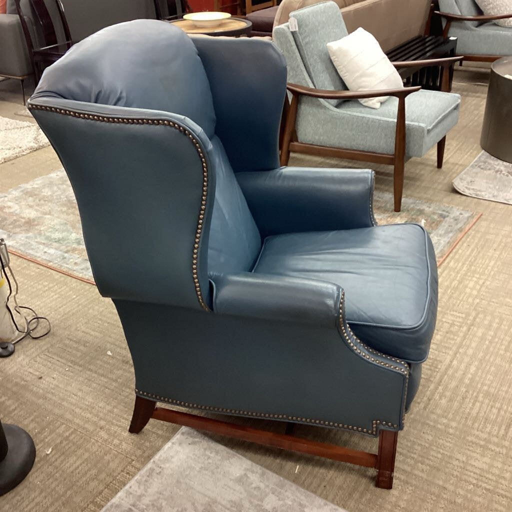 Blue armchair with wooden legs in a room setting
