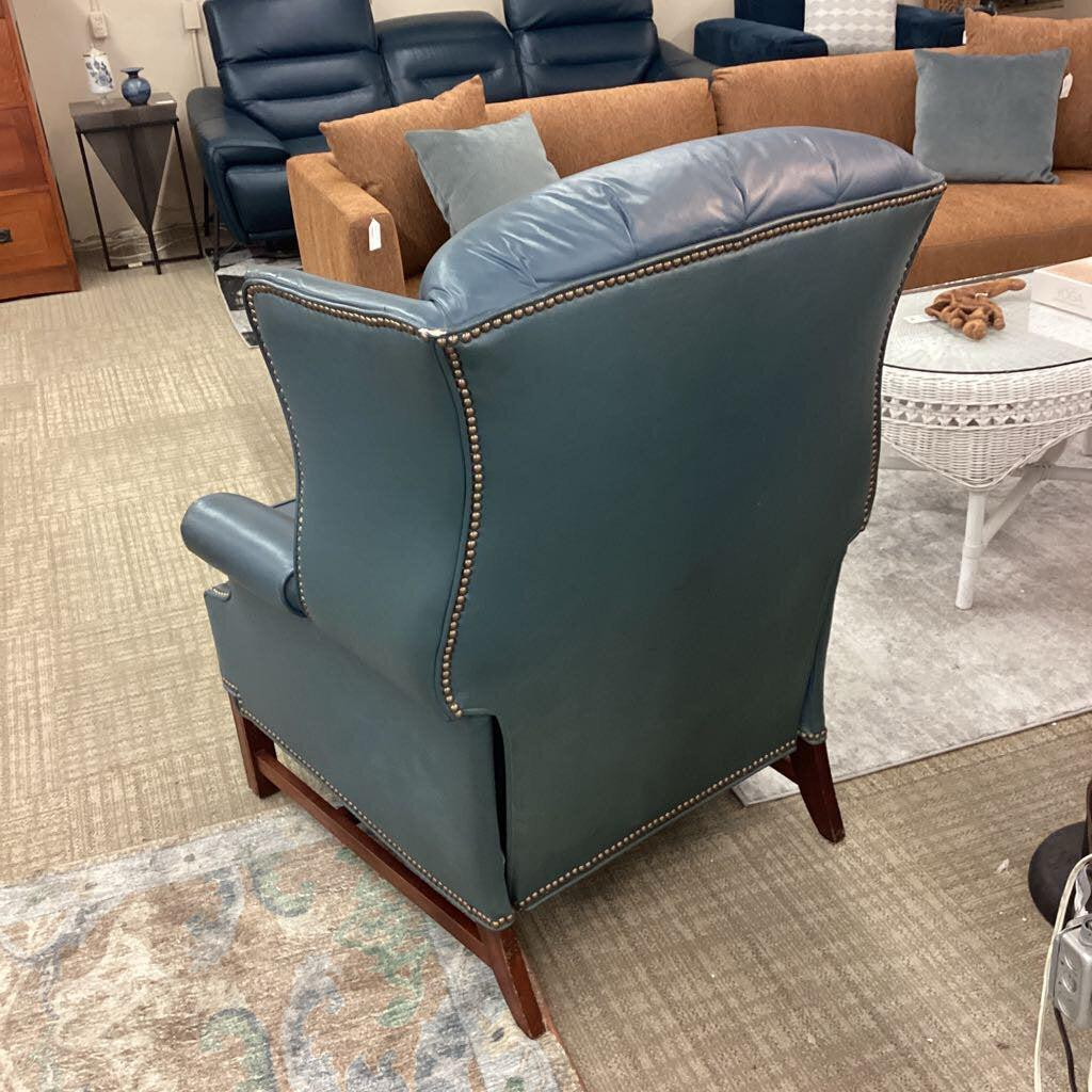 Blue leather armchair in a showroom setting with other furniture.