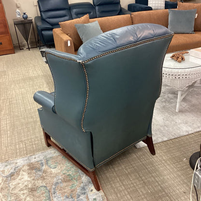 Blue leather armchair in a showroom setting with other furniture.