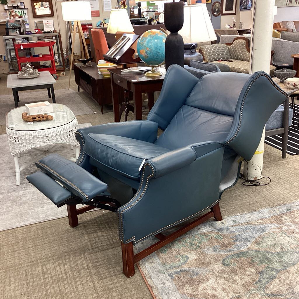 Blue recliner chair in a showroom setting with furniture and decor around.