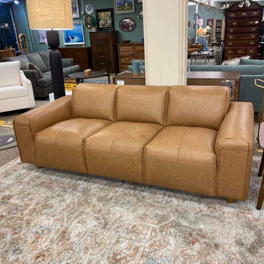 Brown leather sofa in a showroom with other furniture and decor.