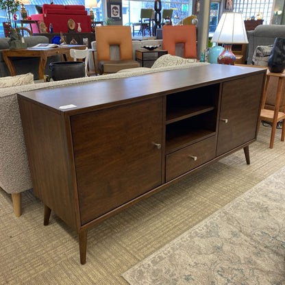 Wooden sideboard in a furniture store setting with chairs and tables in the background.