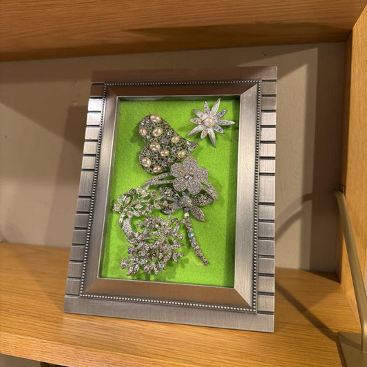 Decorative frame with decorative brooches on a wooden surface