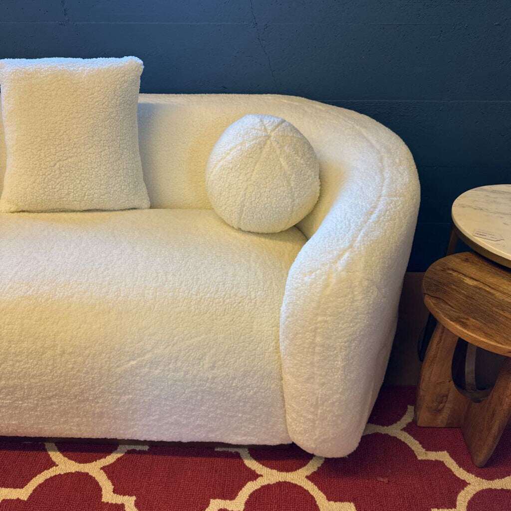 White textured sofa with decorative cushions against a blue wall.