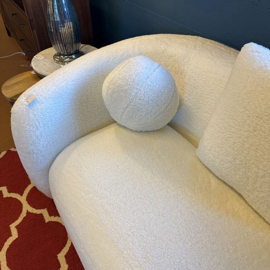 White textured sofa with a round cushion on a red patterned rug