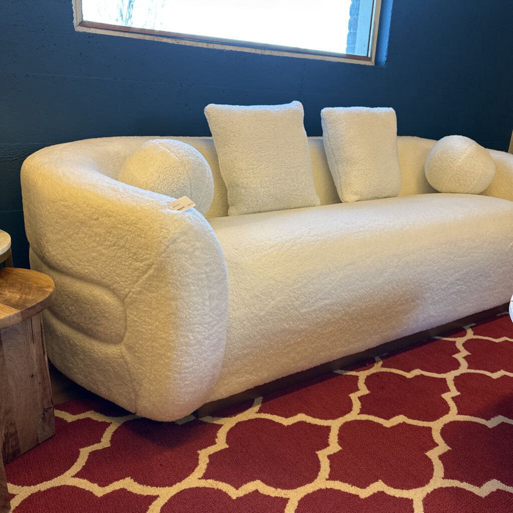 White sofa with cushions on a red patterned rug against a blue wall.