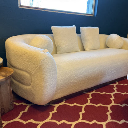 White sofa with cushions on a red patterned rug against a blue wall.