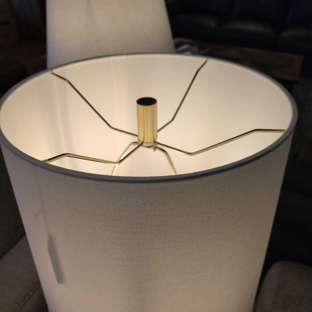 Close-up of a lamp with a cracked white shade and gold metal base.