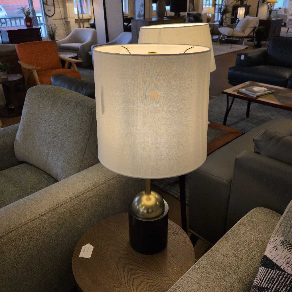 Lamp on a table in a living room setting with furniture and decor.