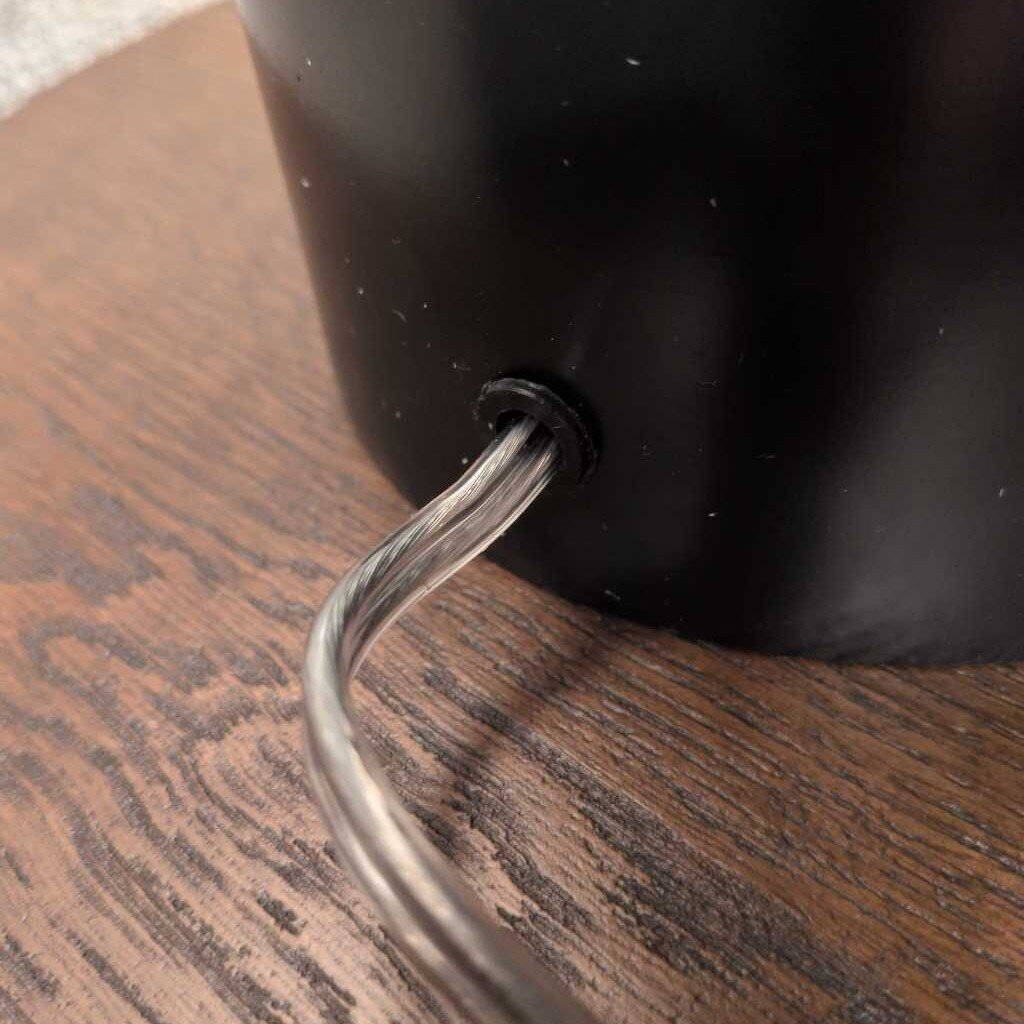 Black lampshade with a metallic hook on a wooden surface
