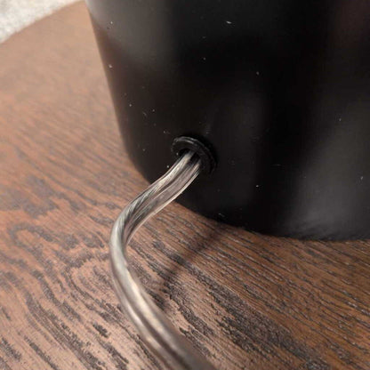 Black lampshade with a metallic hook on a wooden surface