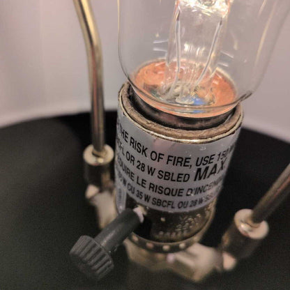 Close-up of a light bulb with a warning label on a black surface.