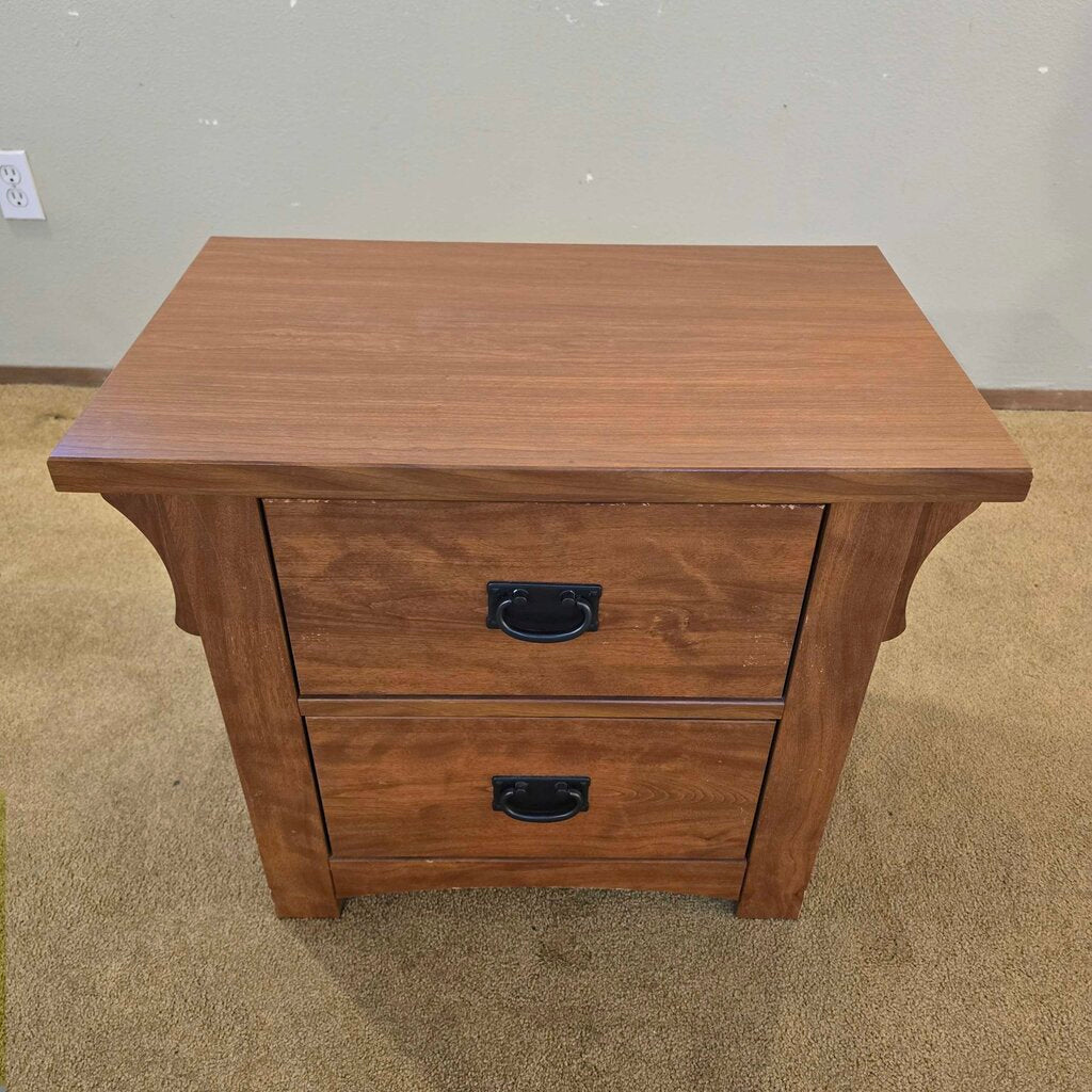 Wooden nightstand with two drawers on a carpeted floor.