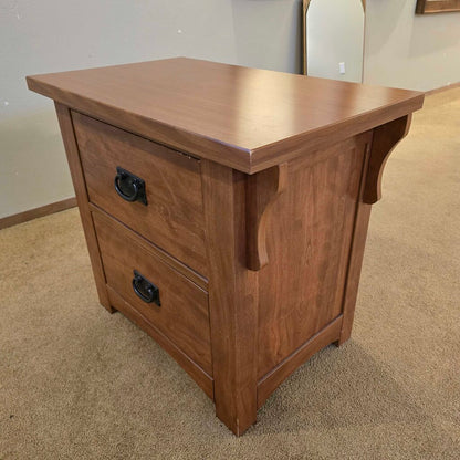 Wooden nightstand with two drawers on a carpeted floor.