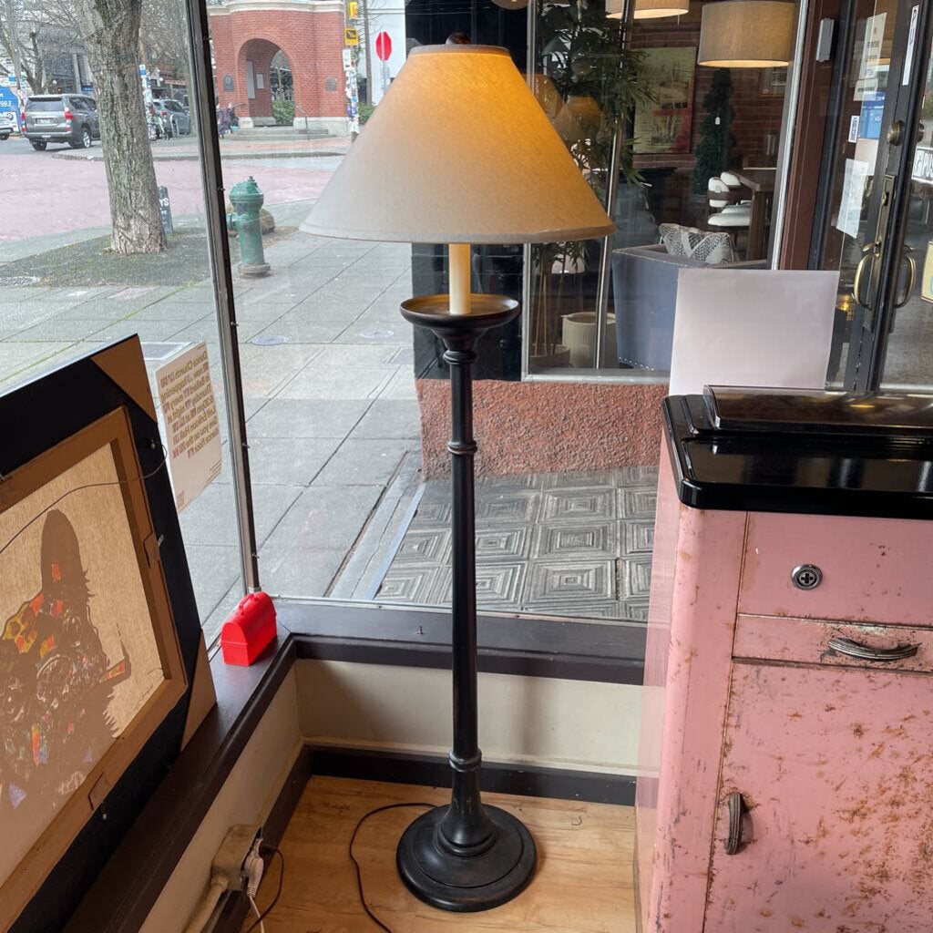 Floor lamp with a beige shade in a room with a pink cabinet and a computer screen.
