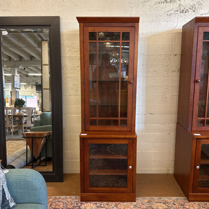 Wooden corner cabinet with glass doors in a room setting
