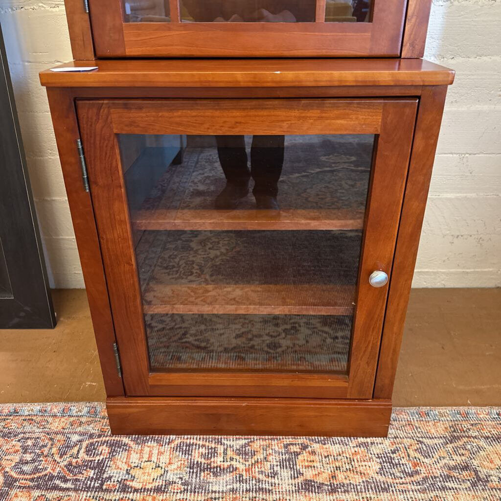 Wooden cabinet with glass door on a patterned rug