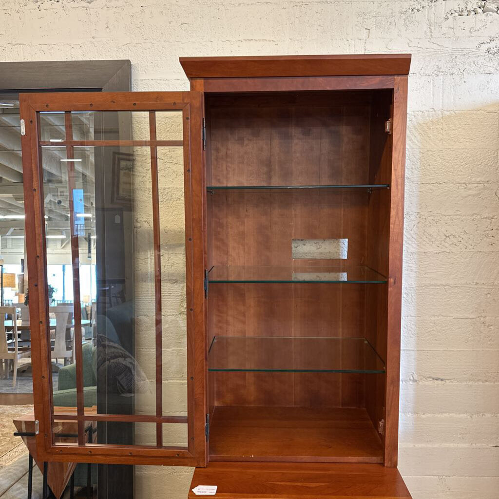 Wooden bookshelf with glass doors in a room setting