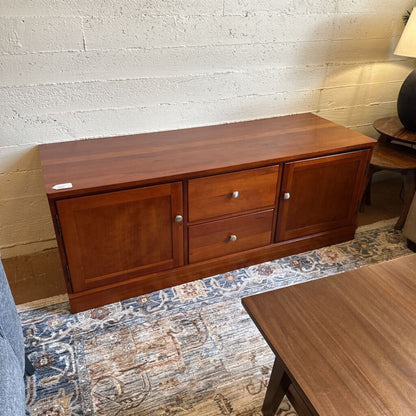 Wooden sideboard with drawers against a textured wall.