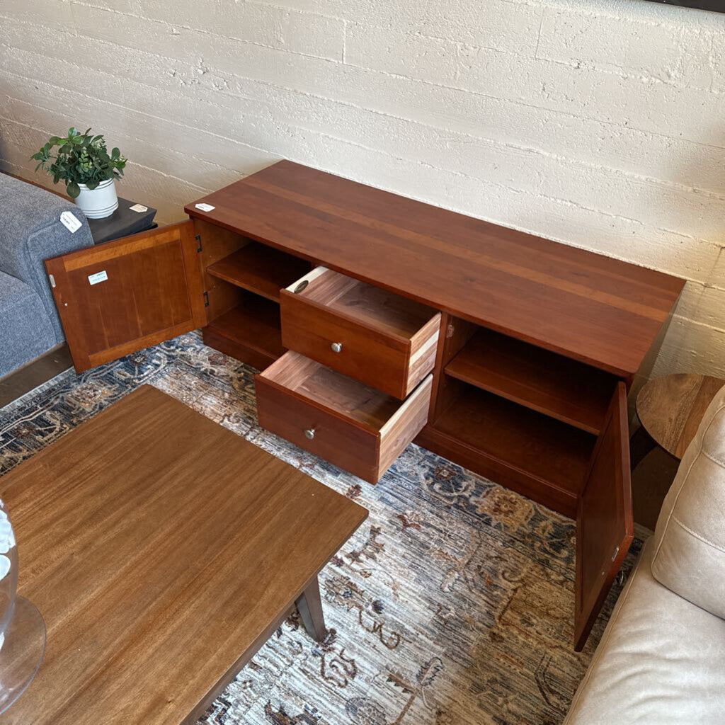 Wooden entertainment console in a living room setting with a sofa and coffee table.