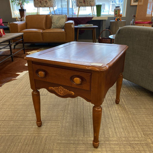 Wooden side table in a living room setting with furniture and decor.