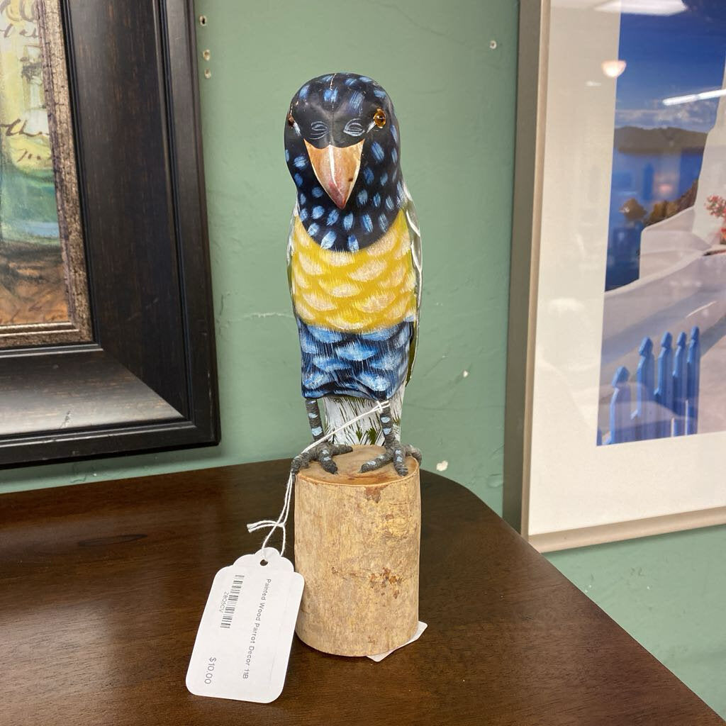 Decorative bird figurine on a cork base with a tag, displayed against a green wall with framed pictures.