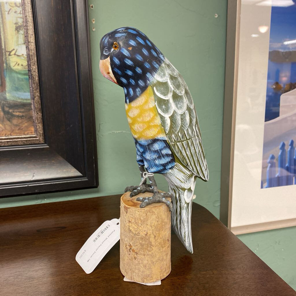 Colorful parrot figurine on a cork base with a tag, placed on a wooden surface.