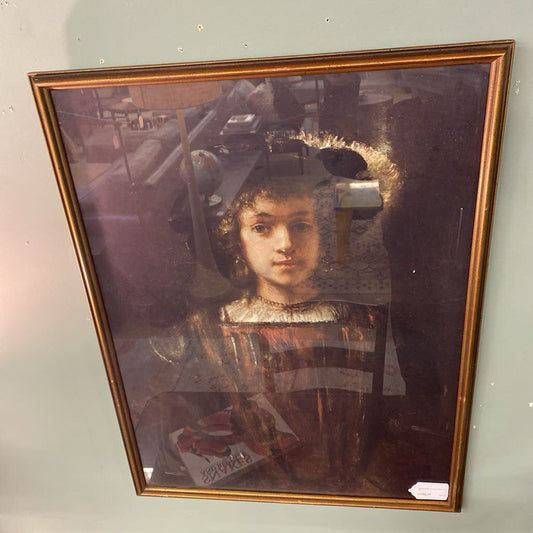 Framed portrait of a young girl with a gold frame on a light gray wall.