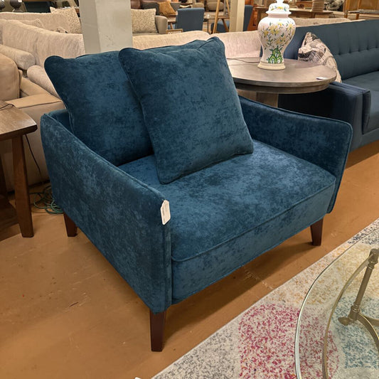 Blue velvet armchair with cushions in a furniture store setting