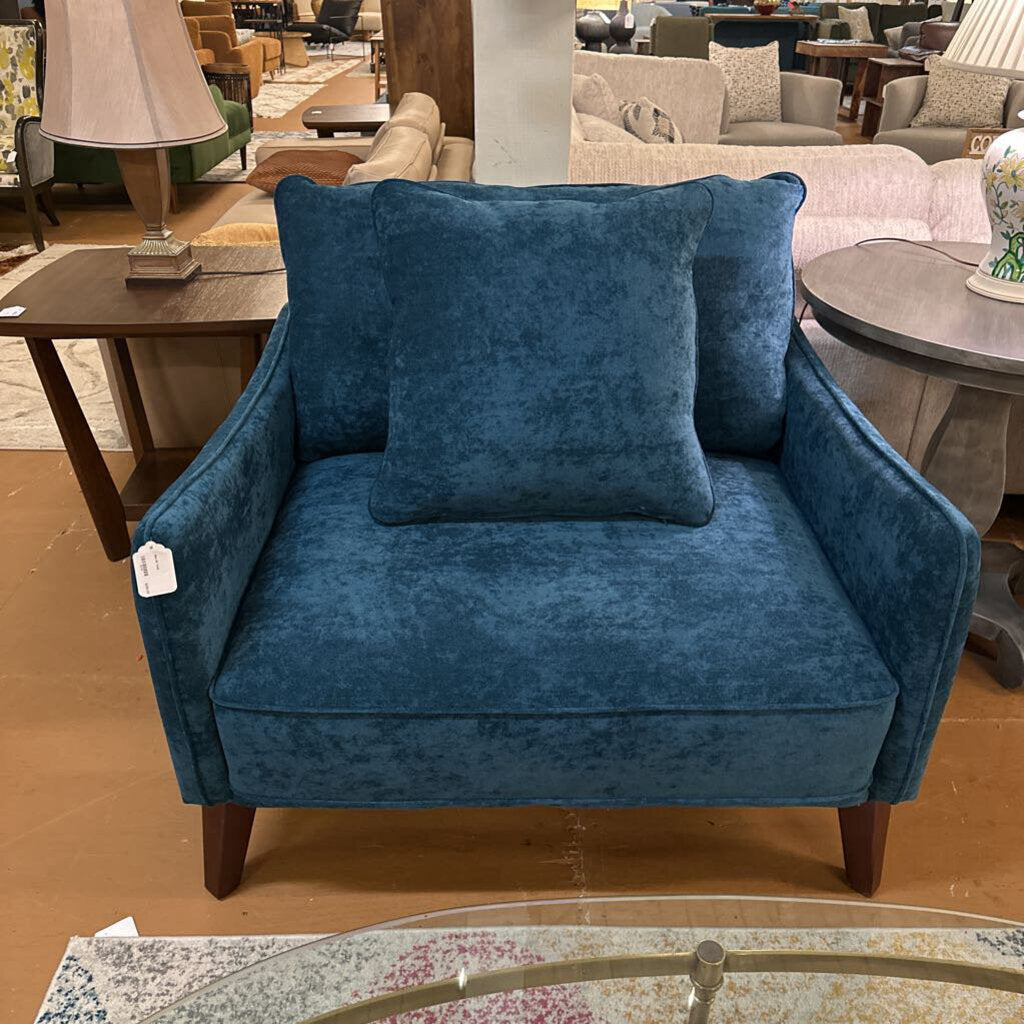 Blue armchair with decorative pillows in a furniture store setting