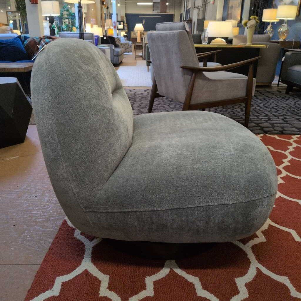 Gray armchair in a showroom with other furniture and decor items.