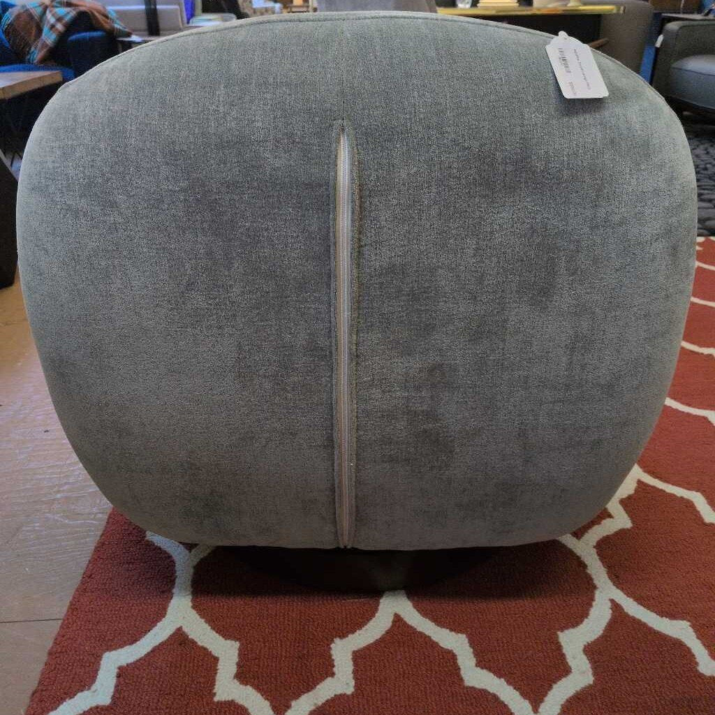 Gray fabric ottoman with a metallic handle on a patterned rug